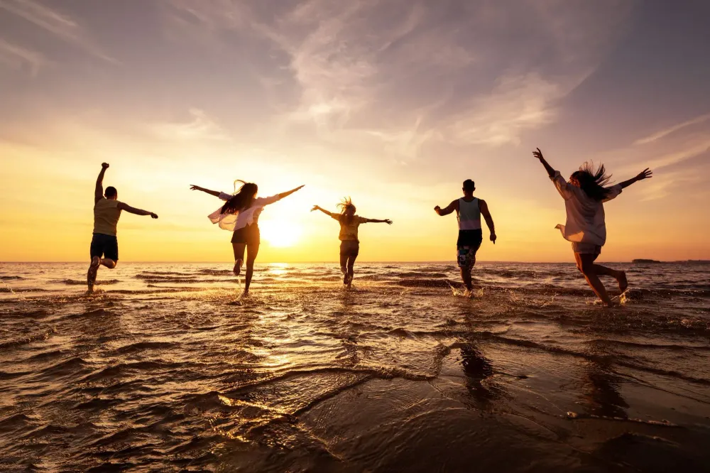 Silhouette of group of friends running into the ocean